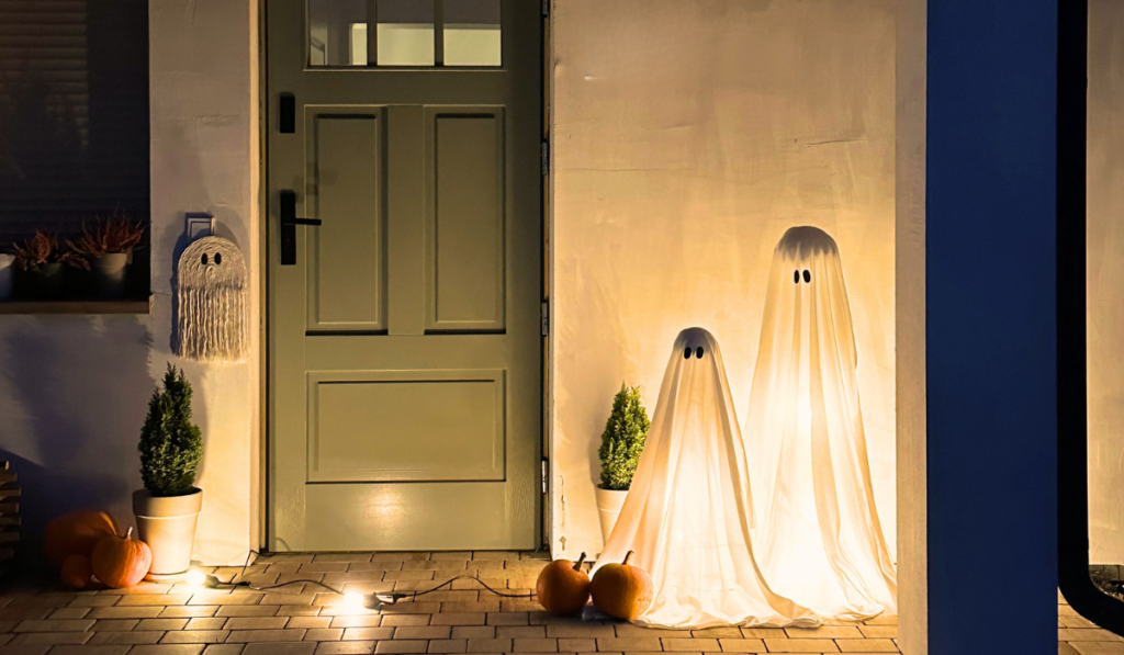 Halloween duchovia z plachty postavení pred domom.